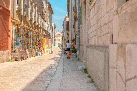 Picturesque Mediterranean street with outdoor cafes and people walking in the summer sun. Mediterranean alley with old architecture and colorful accents. European travel and culture conceptの写真素材