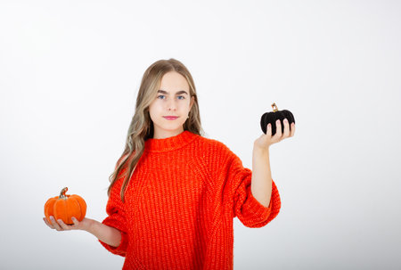 Halloween celebration concept. Portrait smiling girl in orange clothes, with pumpkin jack for sweet candy. Halloween decor. Isolated on white backgroundの写真素材