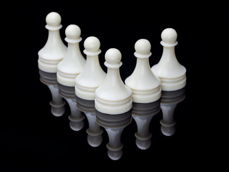 Symmetrical lineup of white chess pieces on reflective surface, symbolizing strategy, balance and competition.の写真素材