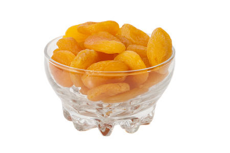 Dried apricots in glass bowl isolated on white の写真素材