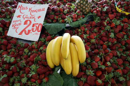 strawberries in the basins on green leaves, pineapple and bananasの写真素材