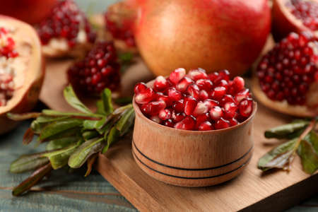 Delicious ripe pomegranate kernels in bowl on wooden board, closeupの写真素材