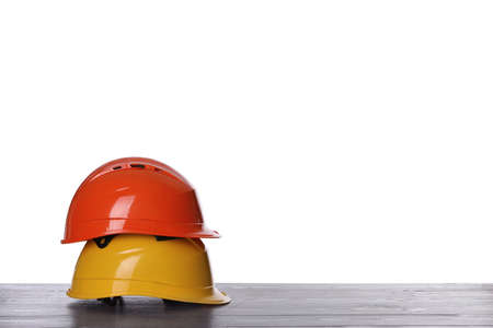 Different hard hats on wooden table against white background. Space for textの写真素材