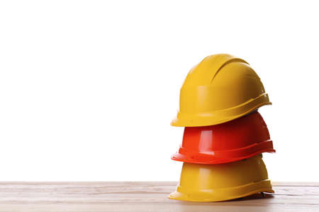 Different hard hats on wooden table against white background. Space for textの写真素材