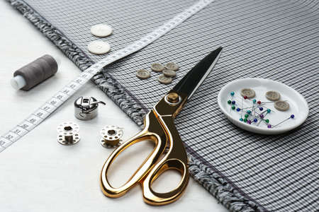 Composition with different sewing supplies and fabric on white wooden table