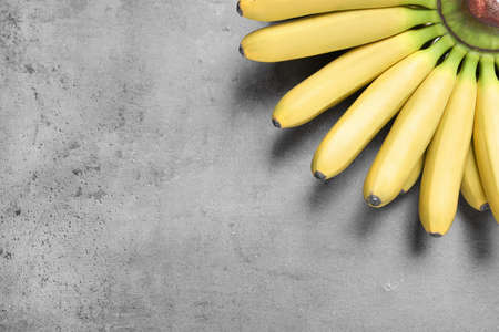 Bunch of ripe baby bananas on grey table, top view. Space for textの写真素材