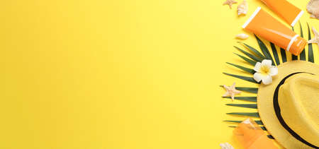 Sun protection products and beach accessories on yellow background, flat lay. Space for text