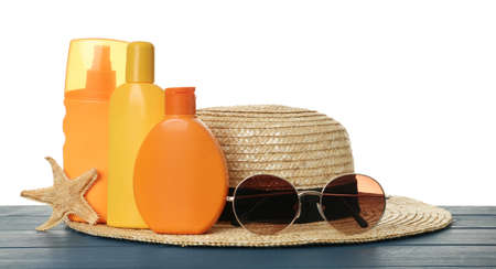 Sun protection products and beach accessories on blue wooden table