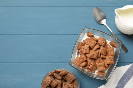 Tasty corn pads with milk served on light blue wooden table, flat lay. Space for text