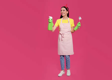Young housewife with detergent and brush on pink backgroundの写真素材