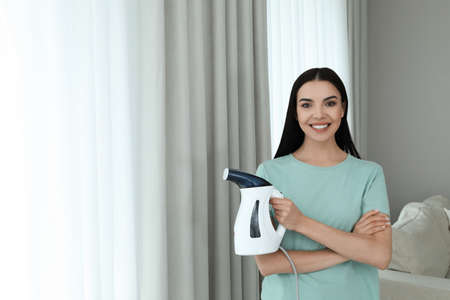 Happy woman with steam iron at home. Space for textの写真素材