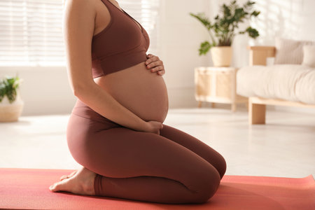 Young pregnant woman practicing yoga at home, closeupの写真素材