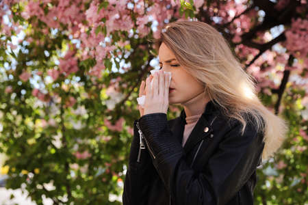 Woman suffering from seasonal pollen allergy near blossoming tree outdoorsの写真素材