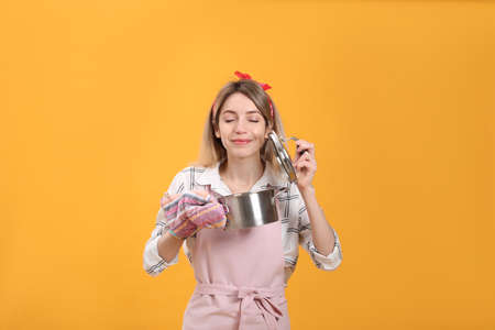Young housewife with pot on yellow backgroundの写真素材