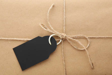 Parcel wrapped in kraft paper with tag as background, closeupの写真素材