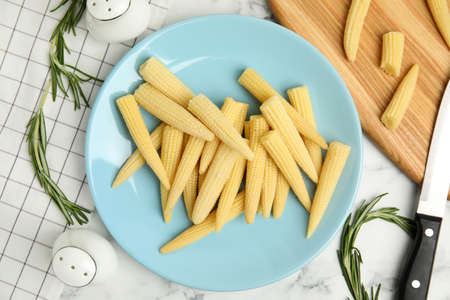 Fresh baby corn cobs on white marble table, flat layの写真素材