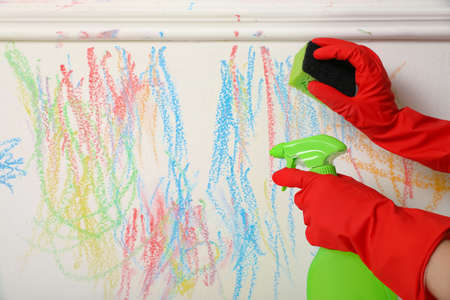 Woman erasing child's drawing from white wall, closeupの写真素材