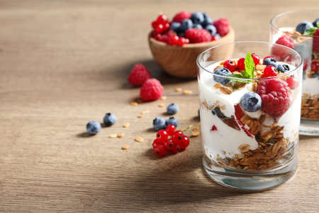 Tasty dessert with yogurt, berries and granola on wooden table. Space for textの写真素材