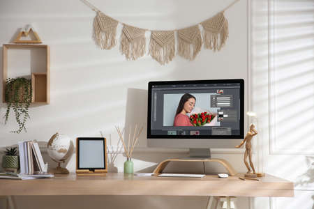 Designer's workplace. Computer with photo editor application on table indoorsの写真素材