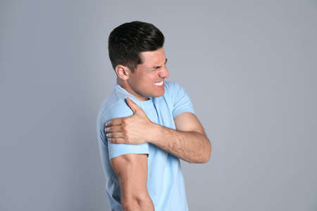 Man suffering from shoulder pain on grey backgroundの写真素材