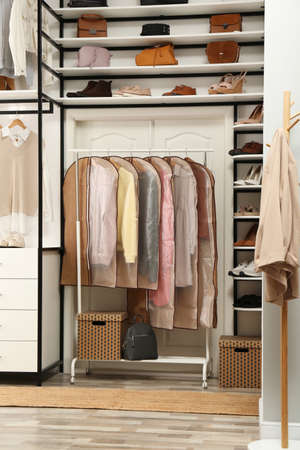 Garment bags with clothes on rack in dressing roomの写真素材