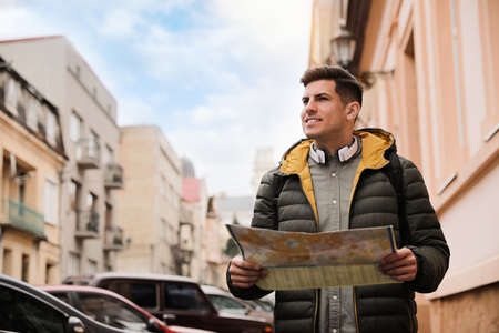 Tourist with map walking on city street