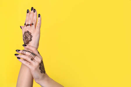 Woman with henna tattoos on hands against yellow background, closeup and space for text. Traditional mehndi ornamentの写真素材