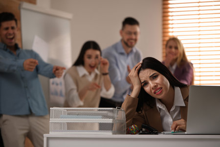 Coworkers bullying their colleague at workplace in office