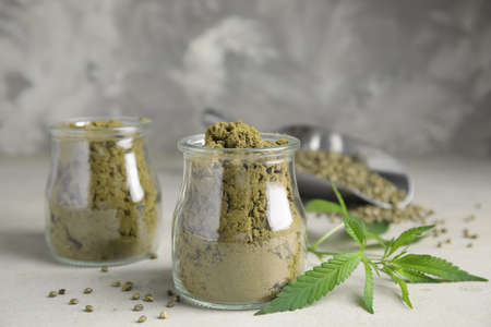Hemp protein powder, seeds and fresh leaves on light gray tableの写真素材