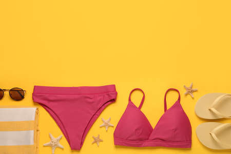 Stylish bikini and beach accessories on yellow background, flat lay. Space for textの写真素材