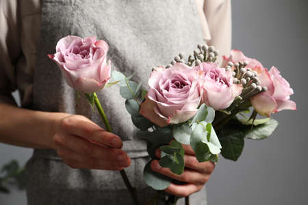 Florist creating beautiful bouquet with roses indoors, closeupの写真素材