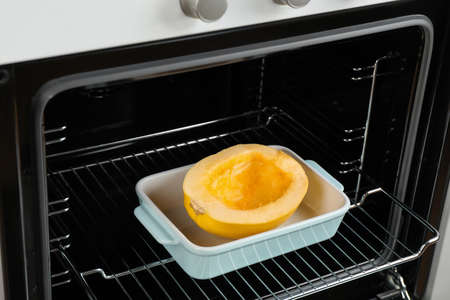 Baking dish with half of fresh spaghetti squash in ovenの写真素材