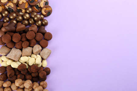 Different delicious chocolate candies on lilac background, flat lay. Space for textの写真素材