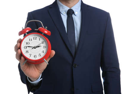 Businessman holding alarm clock on white background, closeup. Time managementの写真素材