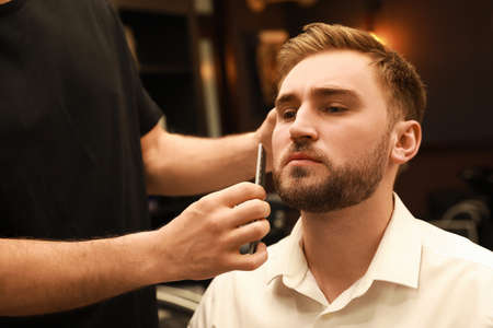 Professional hairdresser working with client in barbershopの写真素材