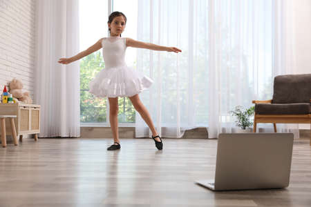 Cute little girl taking online dance class at homeの写真素材
