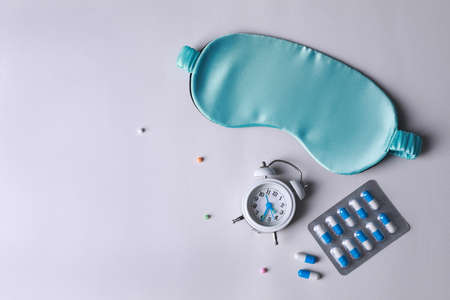 Sleeping mask, alarm clock and pills on white background, flat lay. Insomnia treatmentの写真素材