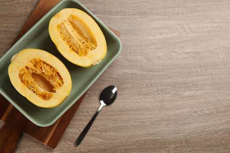 Halves of fresh spaghetti squash in baking dish on wooden table, flat lay with space for text. Cooking at homeの写真素材