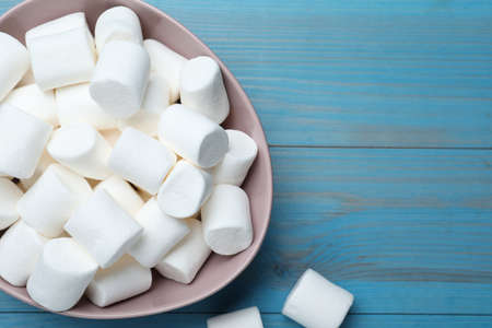 Delicious puffy marshmallows on light blue wooden table, flat lay. Space for textの写真素材