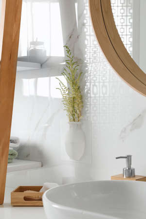 Silicone vase with flowers on white marble wall over countertop in stylish bathroomの写真素材