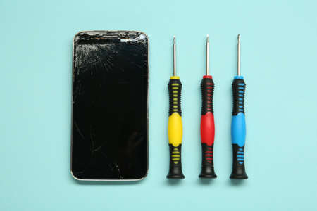 Damaged smartphone and repair tool set on light blue background, flat layの写真素材