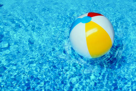 Inflatable beach ball floating in swimming poolの写真素材