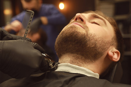 Professional hairdresser working with client in barbershopの写真素材