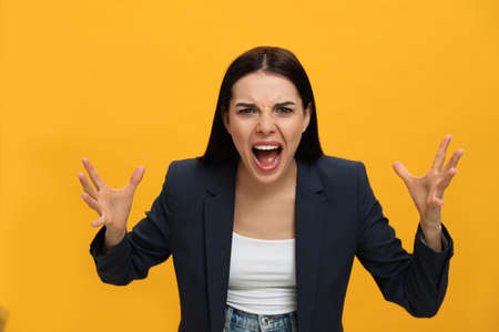 Angry young woman on yellow background. Hate conceptの写真素材