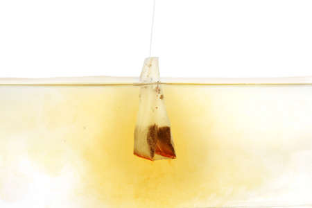 Dipping of tea bag into hot water against white backgroundの写真素材