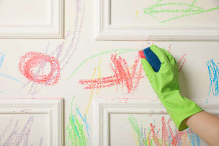 Woman erasing child's drawing from white wall, closeupの写真素材