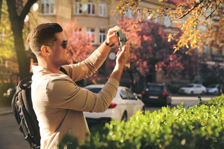 Happy male tourist with camera on city street