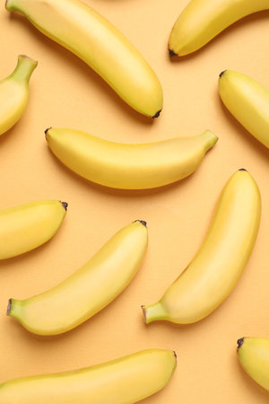 Sweet ripe baby bananas on light orange background, flat layの写真素材