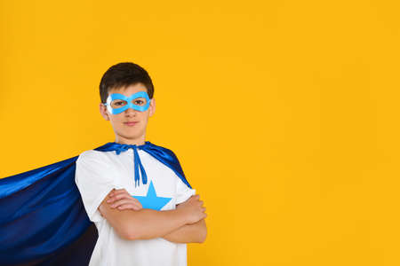 Teenage boy in superhero costume on yellow background. Space for textの写真素材