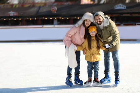 Happy family spending time together at outdoor ice skating rink, space for textの写真素材